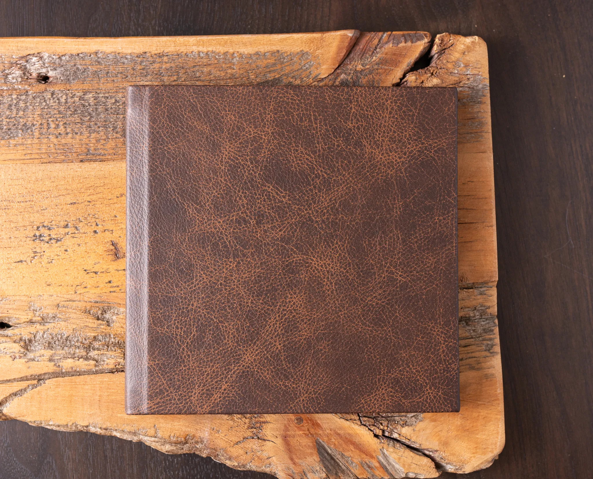 Heirloom leather album resting on a live-edge wood board