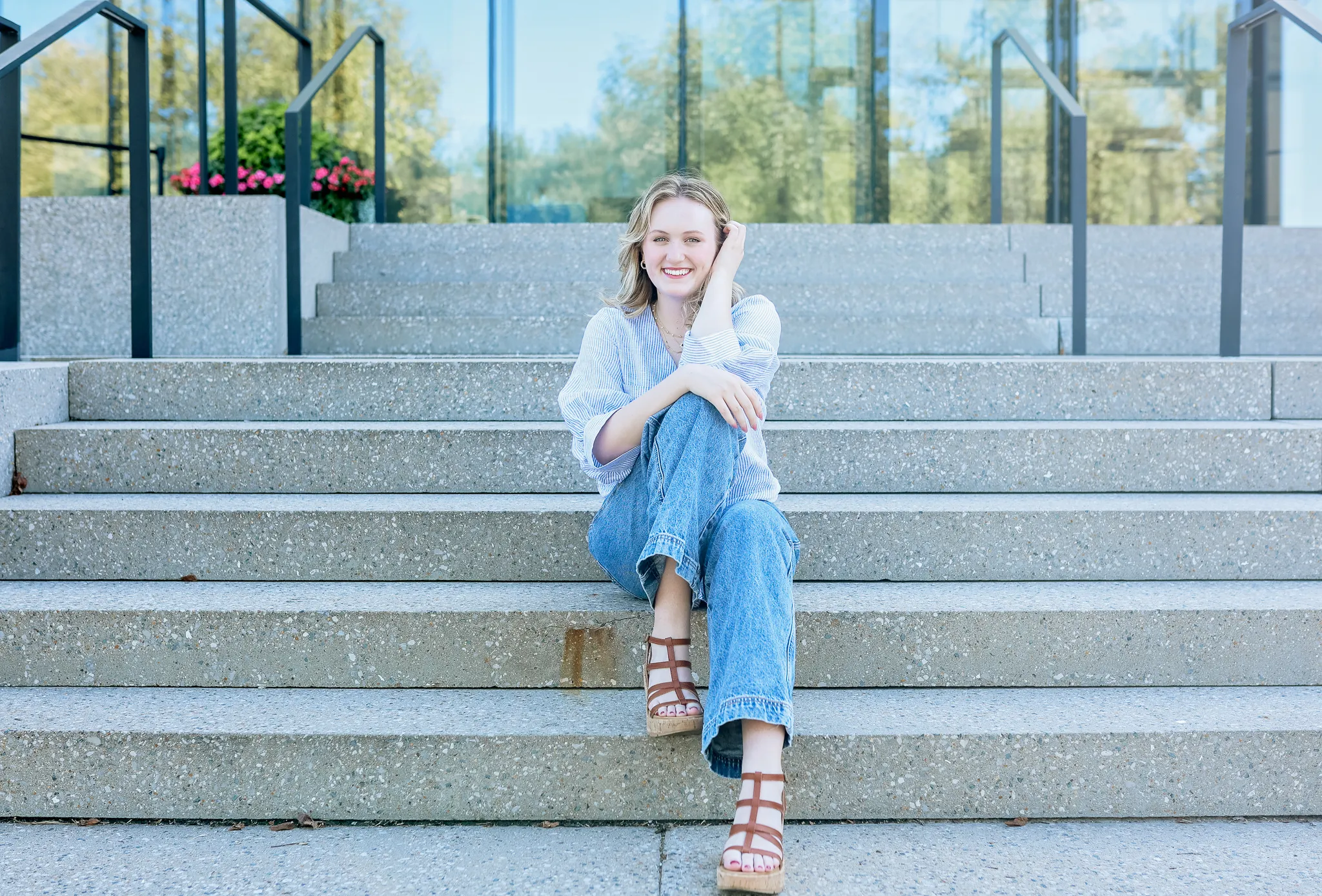 Senior laughing on the sunlit steps of a glass building downtown