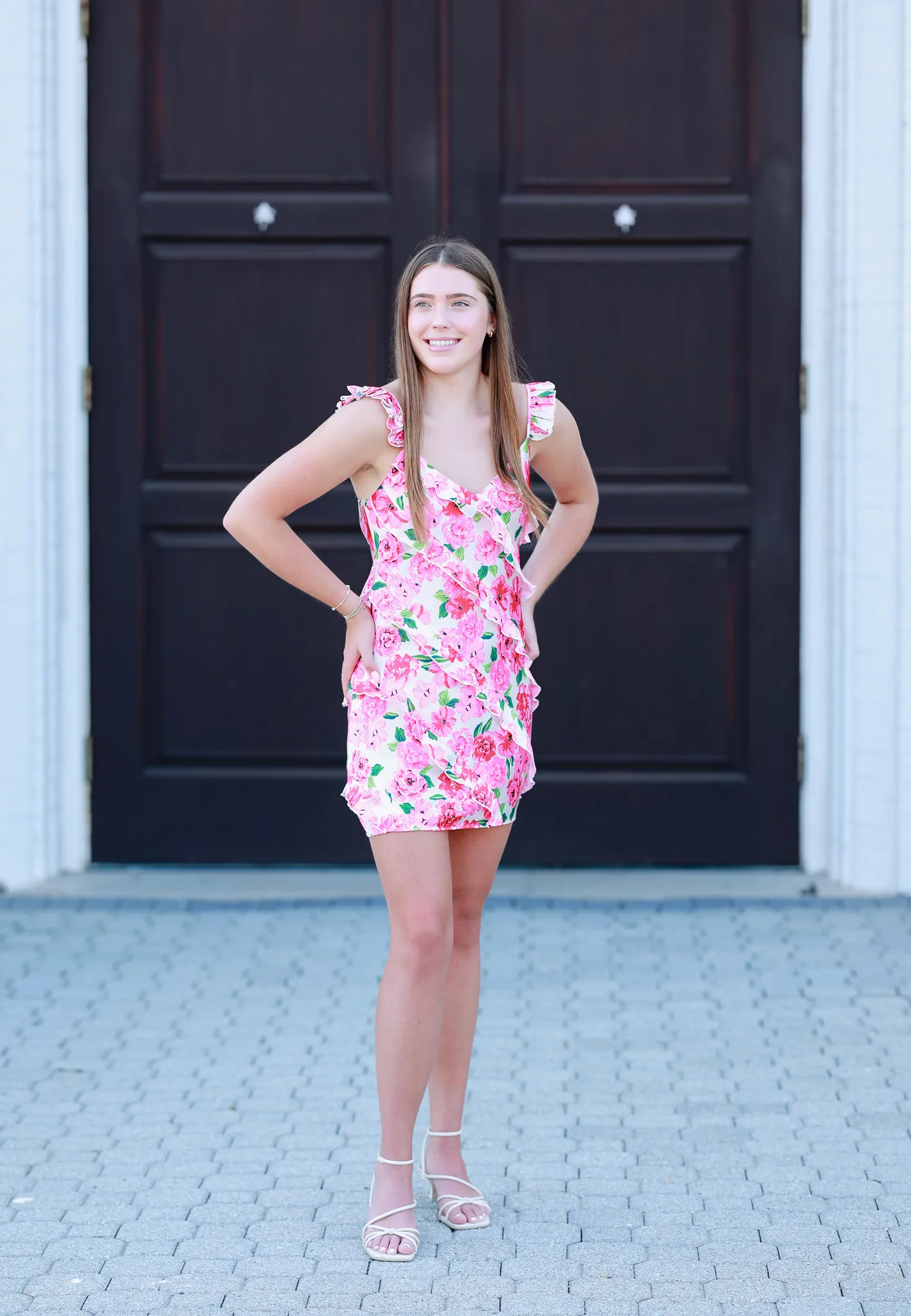 Senior in a pink floral dress in front of dark wooden doors