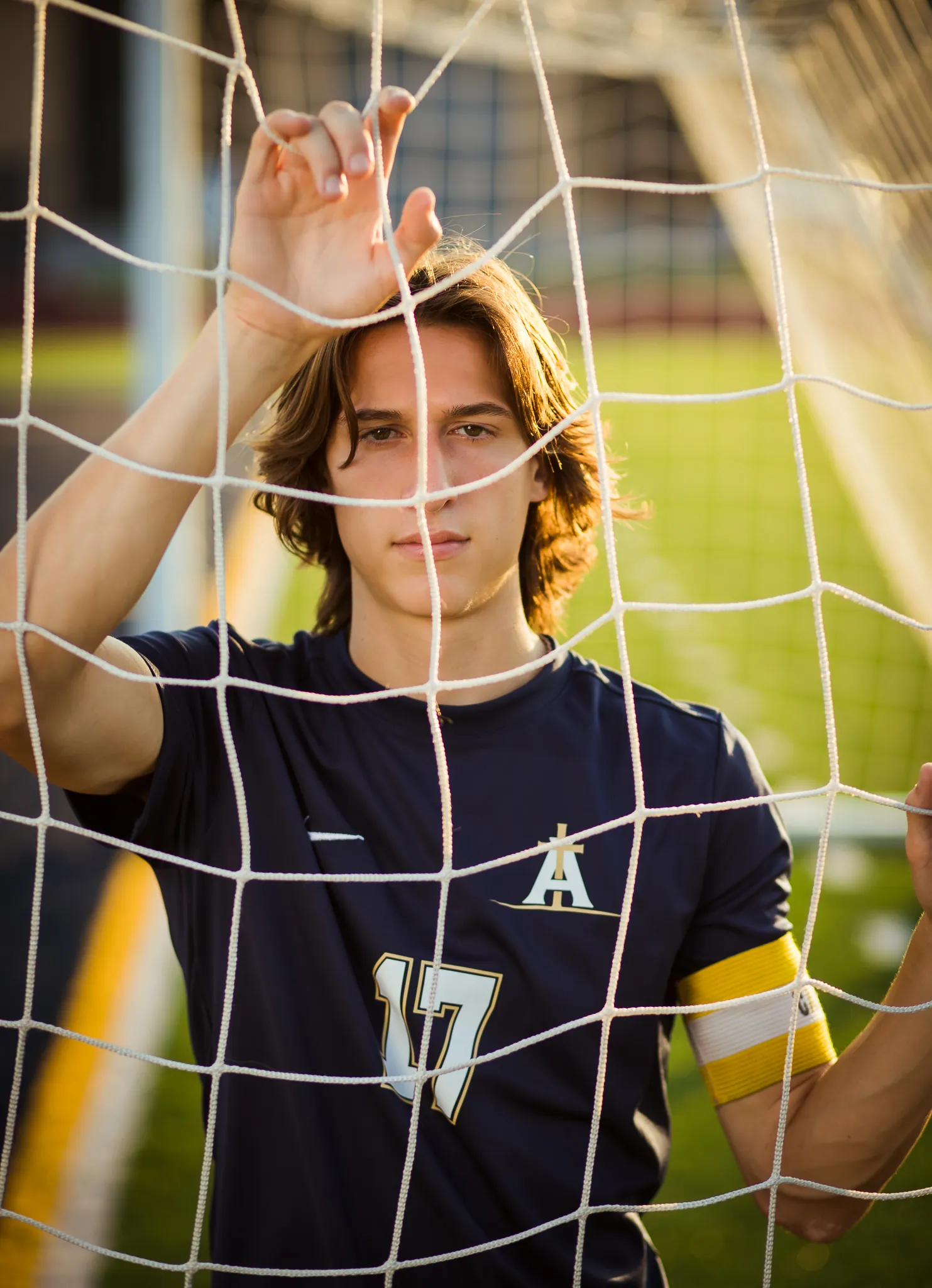 Senior soccer captain looking through the goal net at golden hour